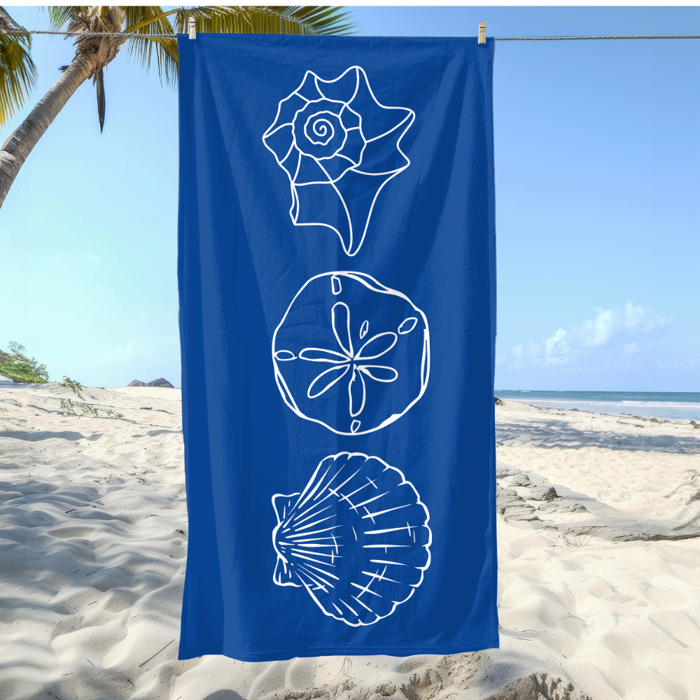 Blue towel with white shell designs on a beach