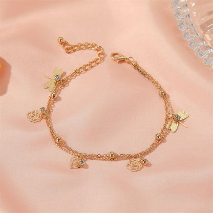 Close-up of delicate rose and dragonfly anklet on a woman’s ankle