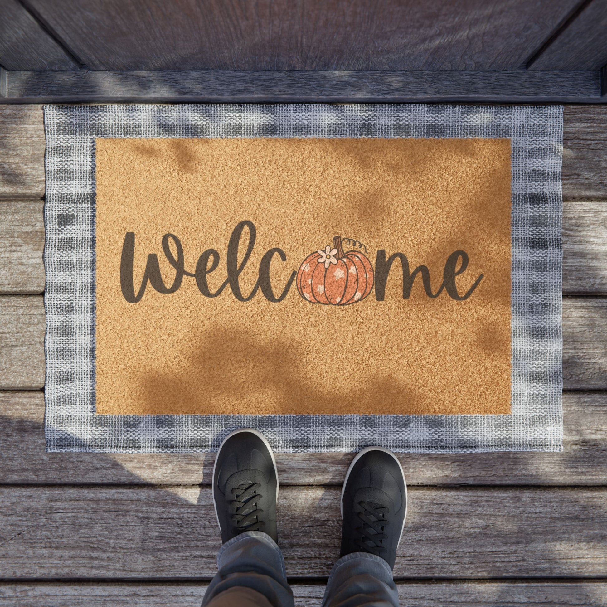 Doormat with 'Welcome' and pumpkin design on a wooden floor