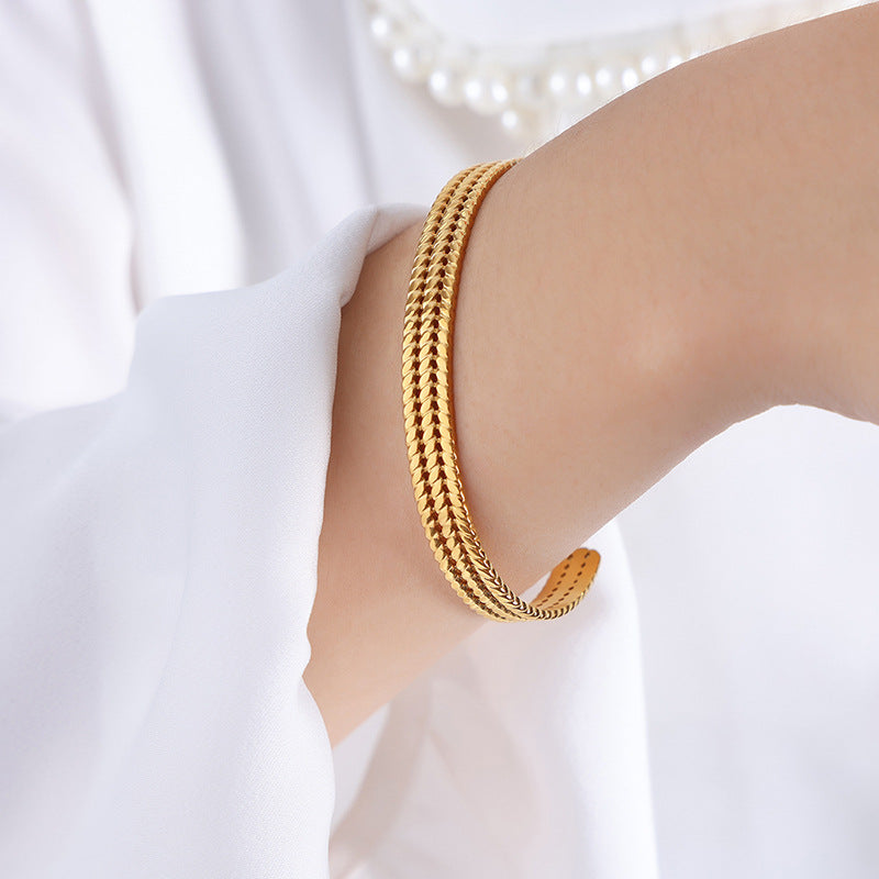 Gold bracelet on a person's wrist with a white background