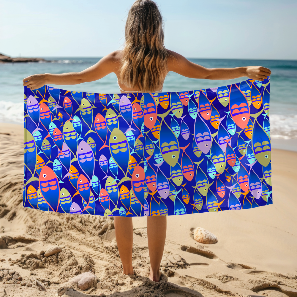 Woman holding a colorful fish-patterned towel on a beach