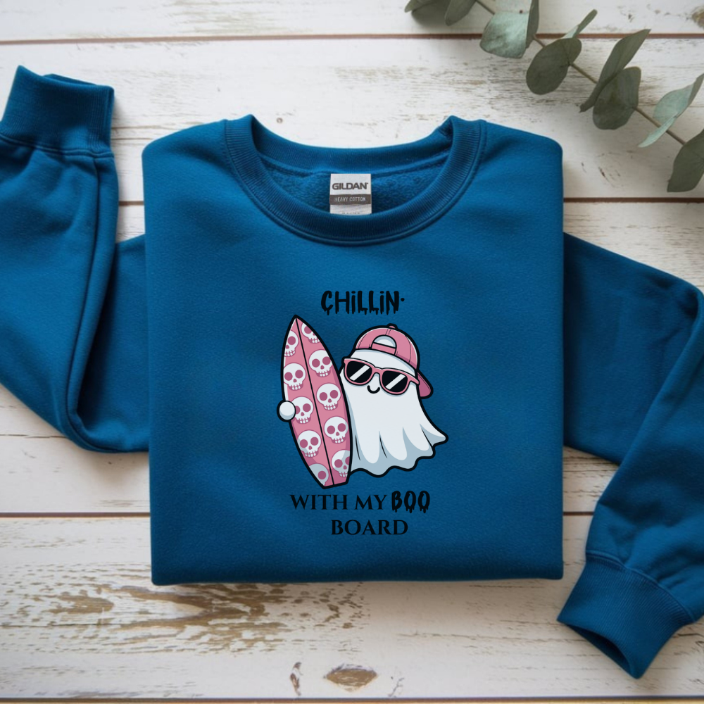 Blue sweatshirt with a ghost and surfboard design on a wooden surface