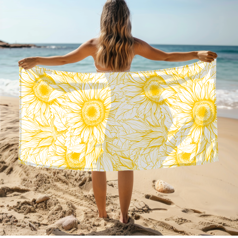 Person holding a yellow and white sunflower-patterned towel on a beach