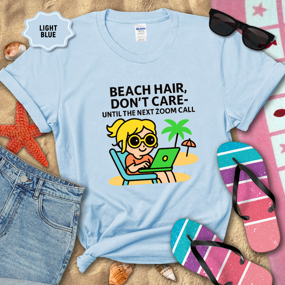 Light blue t-shirt with beach-themed graphic and text on a sandy background with flip-flops and sunglasses.