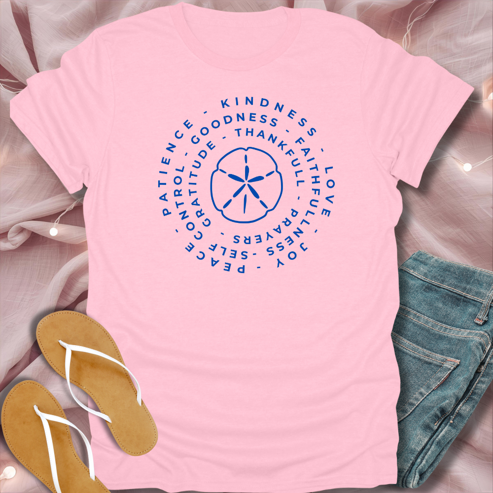 Pink t-shirt with motivational text design on a soft pink background with jeans and sandals.