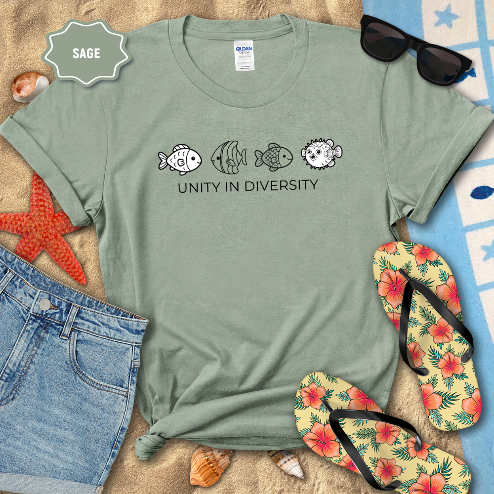 Sage green t-shirt with fish design and 'Unity in Diversity' text, surrounded by beach items.