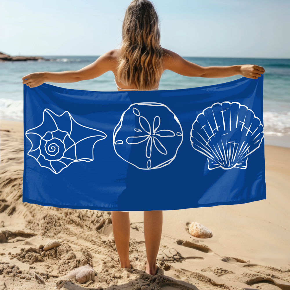 Person holding a blue towel with white shell designs on a beach