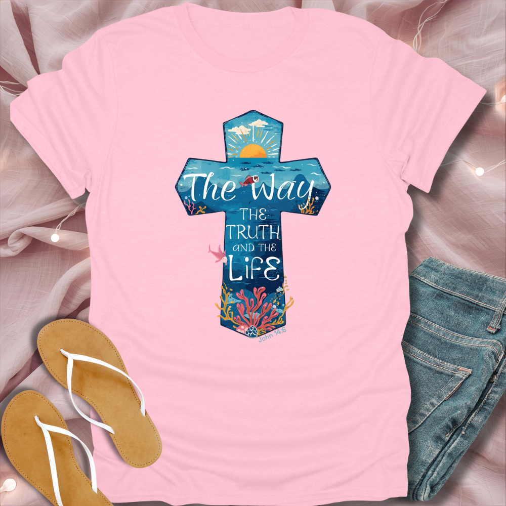 Pink t-shirt with a colorful cross design and text, paired with flip-flops and jeans on a light pink background.
