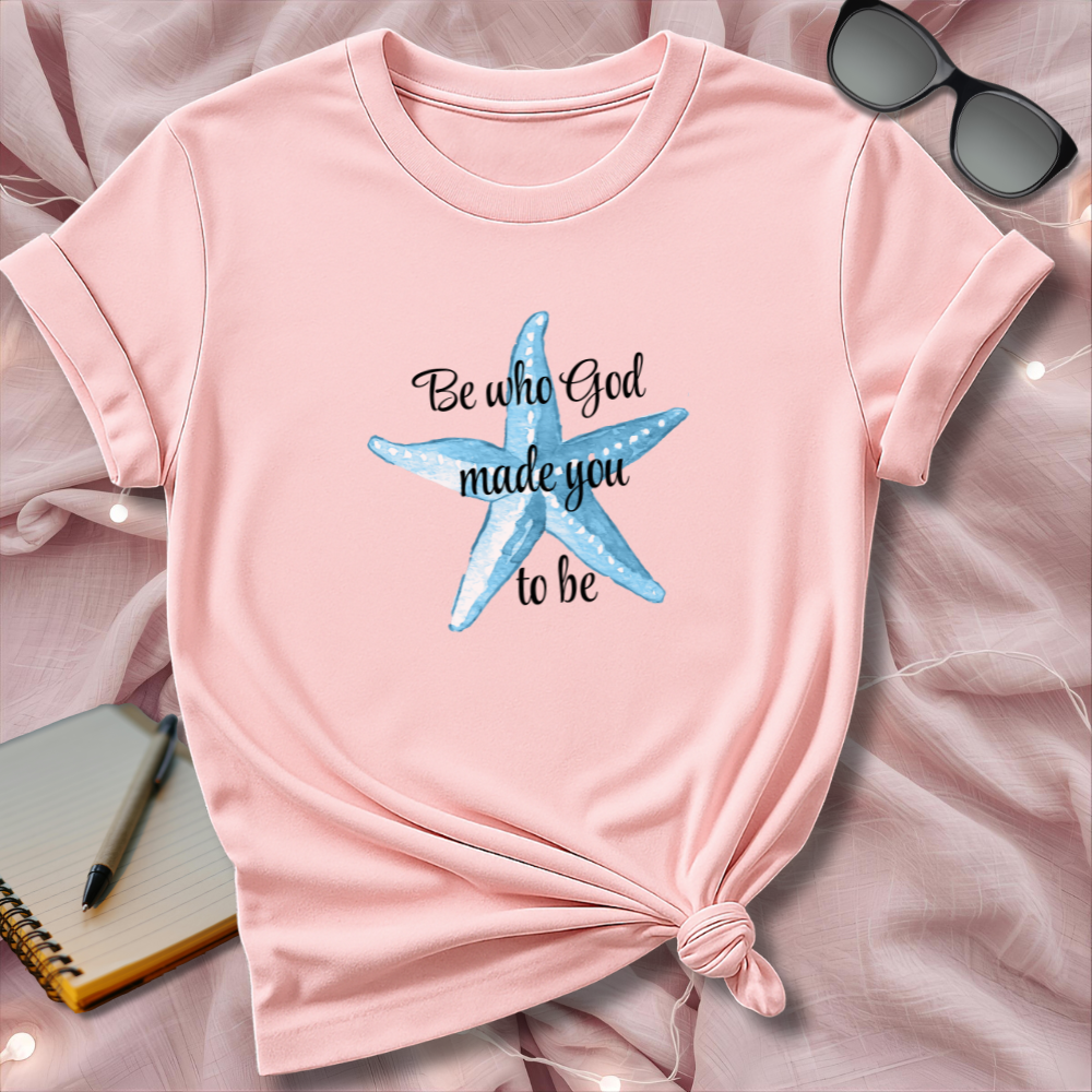 Pink t-shirt with blue starfish design and text on a pink surface.