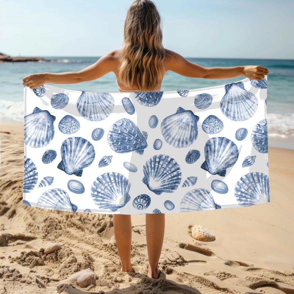Person holding a towel with blue shell pattern on a beach