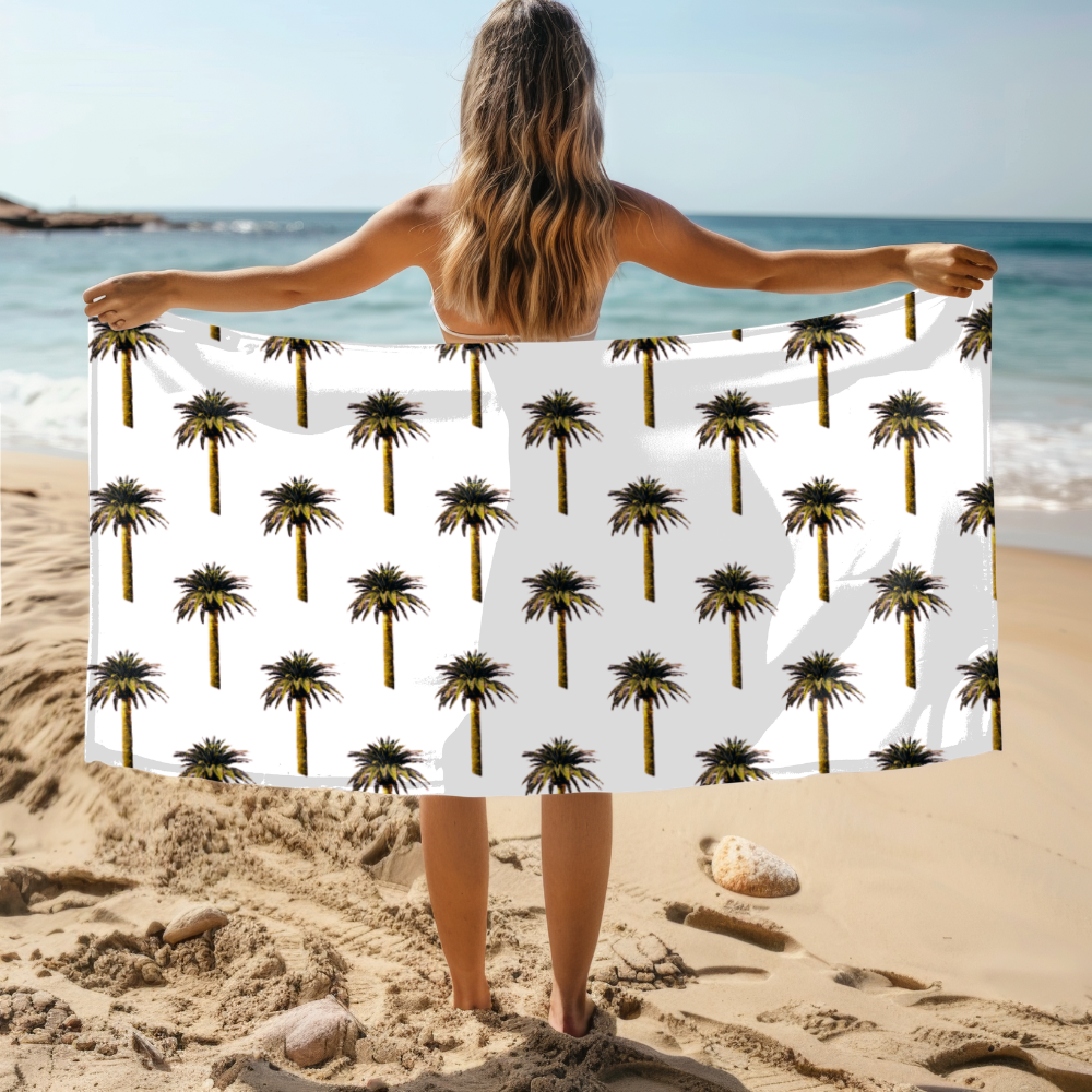 Person holding a towel with palm tree pattern on a beach