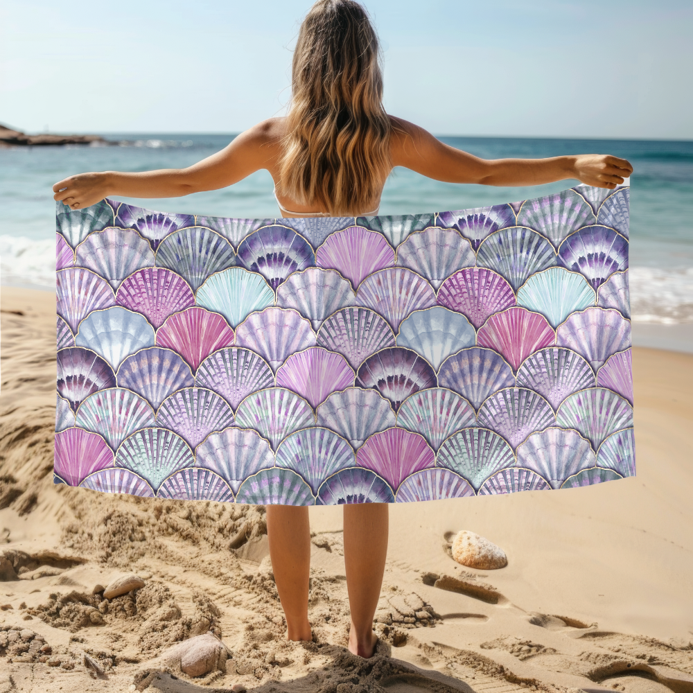 Person holding a colorful shell-patterned towel on a beach