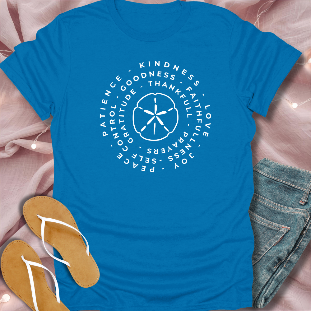 Blue t-shirt with white text and design on a pink surface with sandals and jeans.