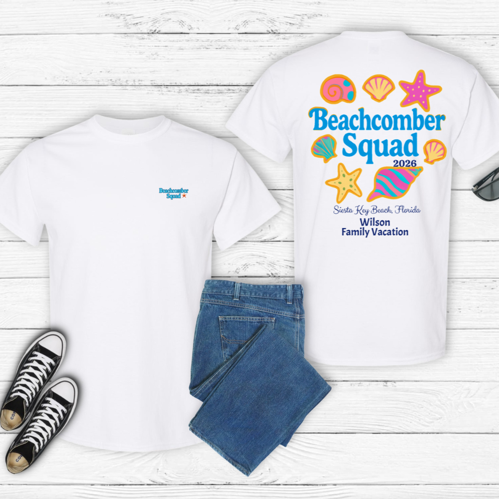 Two white t-shirts with 'Beachcomber Squad' design, blue jeans, and black sneakers on a wooden surface.