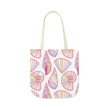 Canvas tote bag with pastel pink, yellow, and blue seashell illustrations on a white background, styled flat on a turquoise wooden surface.