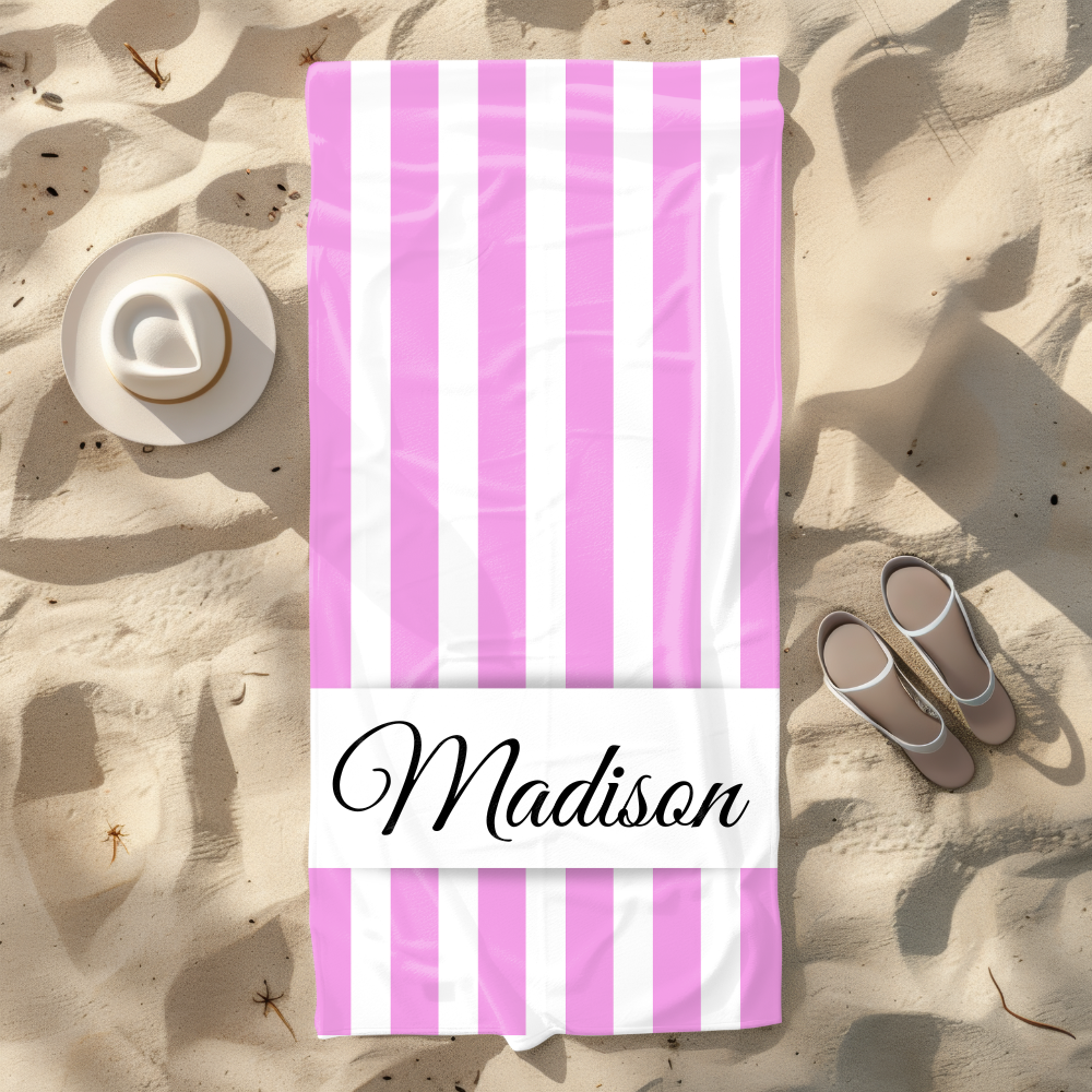 Pink and white striped towel with 'Madison' on a sandy beach