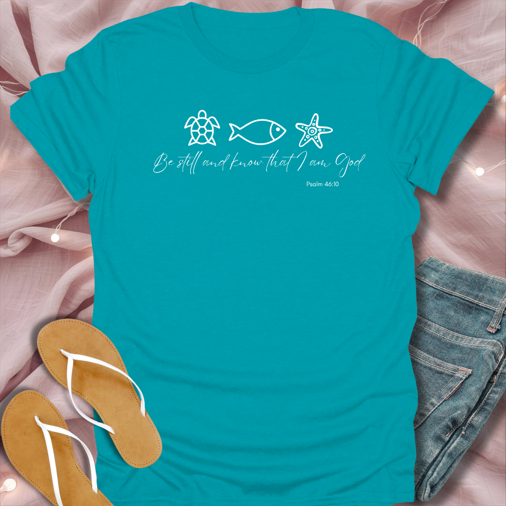 Turquoise t-shirt with ocean-themed design and text on a pink fabric background