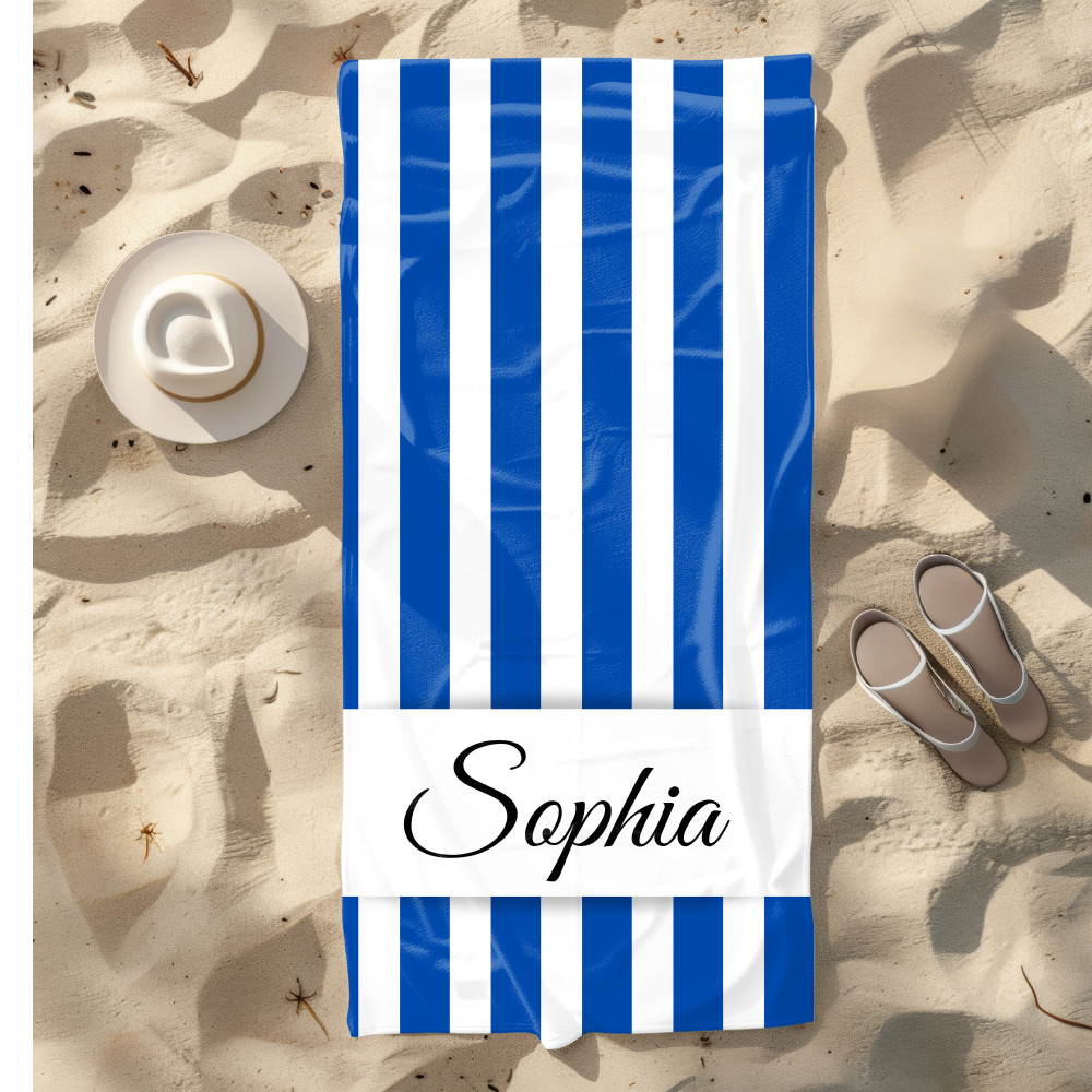 Blue and white striped towel with 'Sophia' on a sandy beach