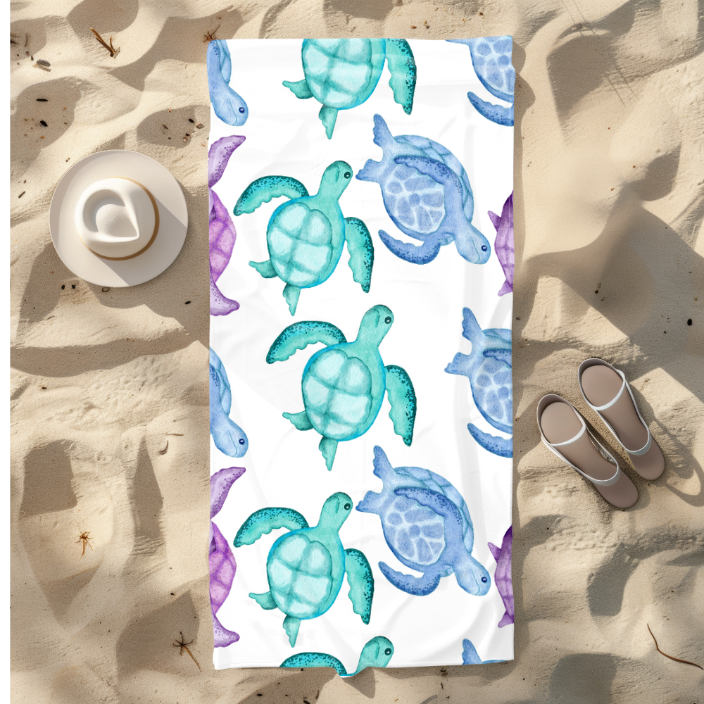 Towel with turtle pattern on a sandy background with sandals and hat.