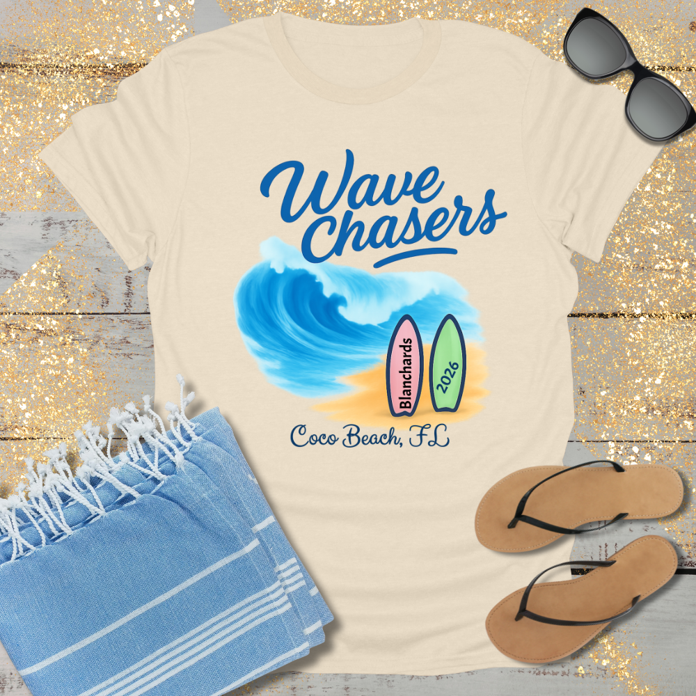 Beige t-shirt with 'Wave Chasers' design, sunglasses, towel, and flip-flops on a wooden surface.