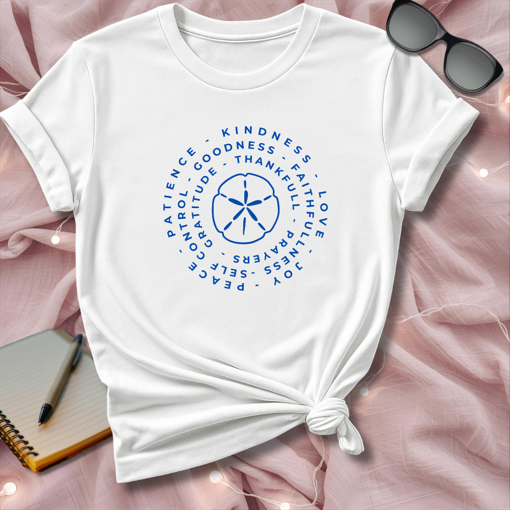 White t-shirt with blue text and design on a pink surface with sunglasses and notebook.