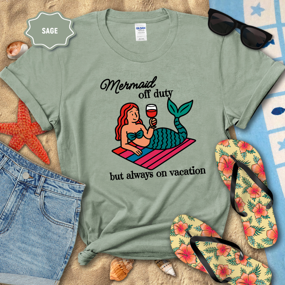 Sage green t-shirt with mermaid graphic and text on a beach setting