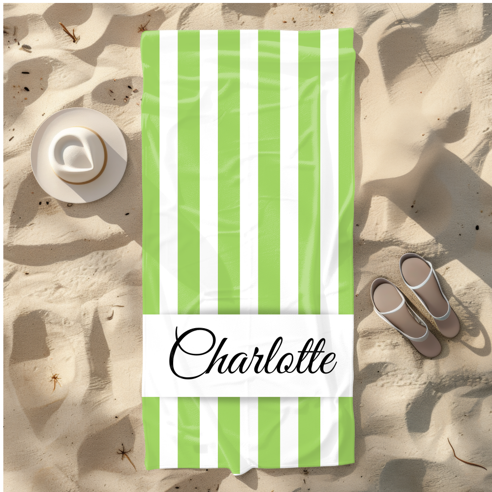 Green and white striped towel with 'Charlotte' on a sandy background