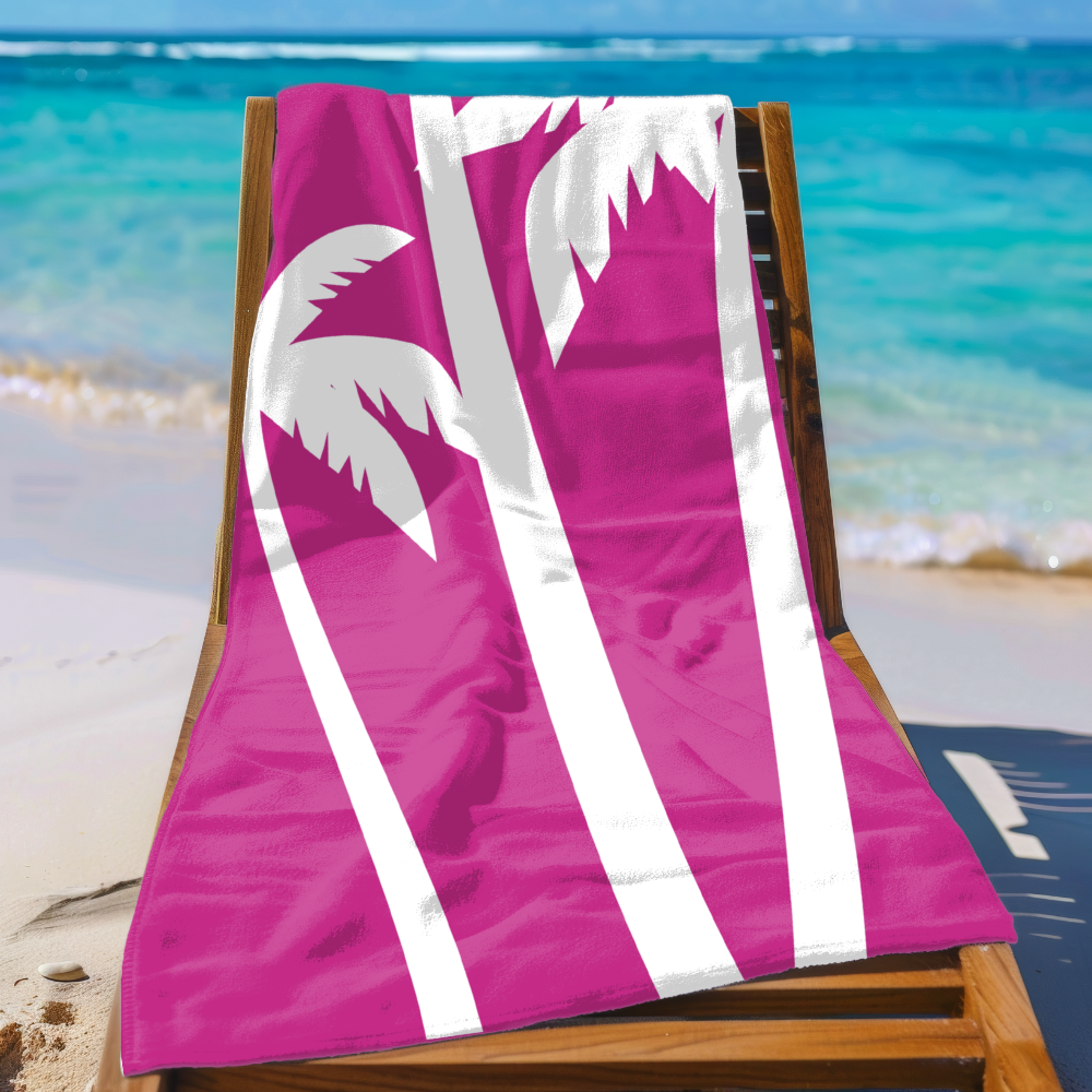Pink beach towel with white palm tree design on a wooden chair at the beach.