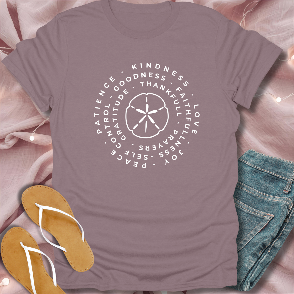Mauve t-shirt with motivational text design on a pink fabric background with flip-flops and jeans.