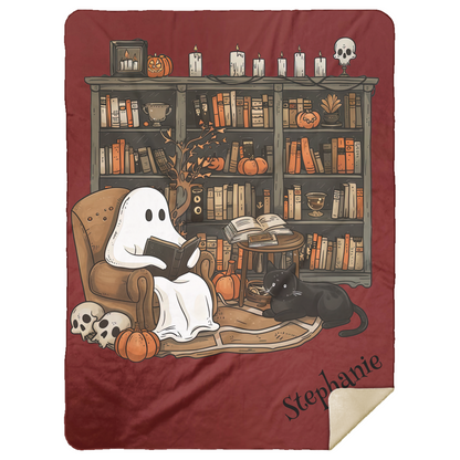 Blanket with a ghost reading a book and a cat in a cozy room setting, featuring pumpkins and candles.