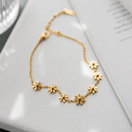 Elegant gold daisy anklet with nature-inspired detailing in soft sunlight