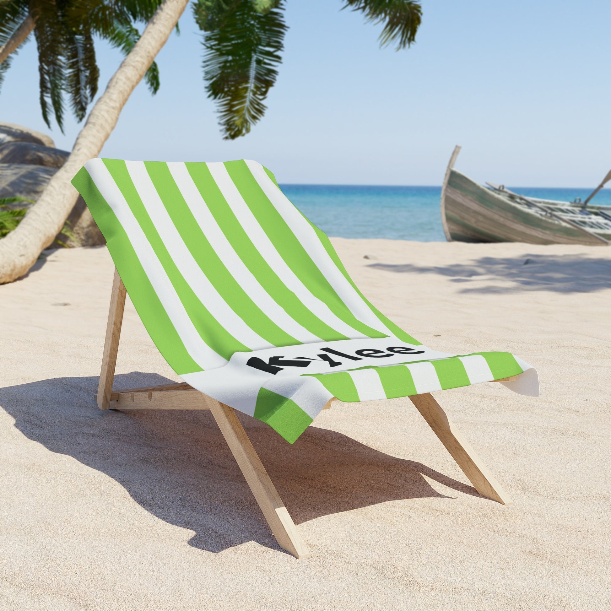 Green and white striped towel on a wooden beach chair with palm trees and ocean in the background