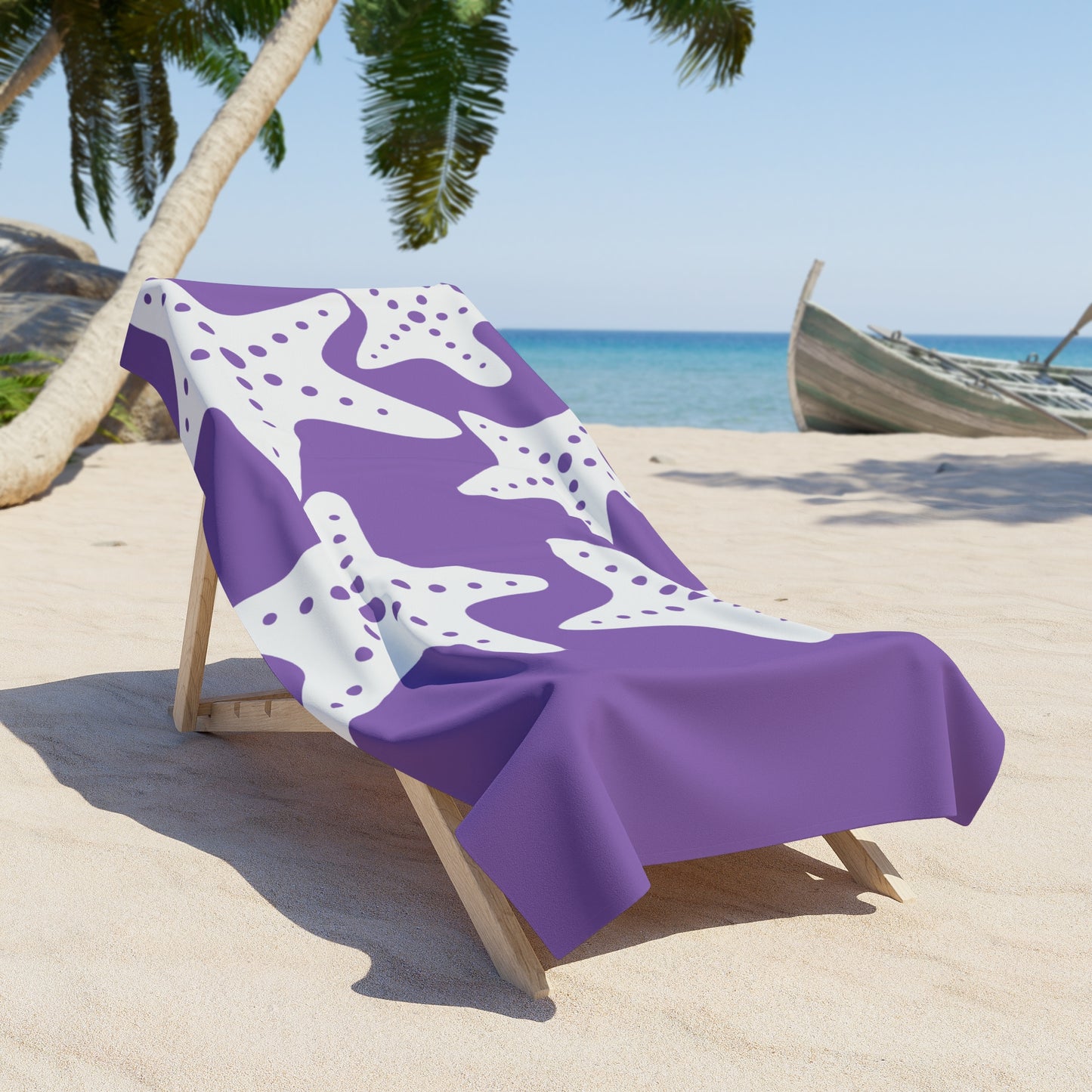 Purple beach towel with white pattern draped over a wooden chair on a sandy beach with palm trees and ocean in the background.