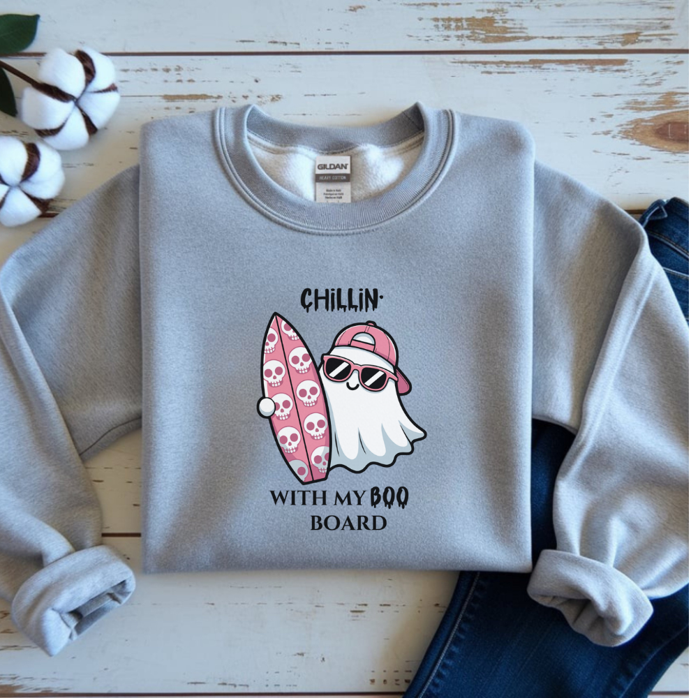 Gray sweatshirt with a ghost and surfboard graphic on a wooden surface.