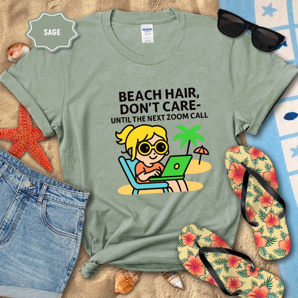 Sage green t-shirt with beach-themed graphic and text on a sandy background with flip-flops and sunglasses.