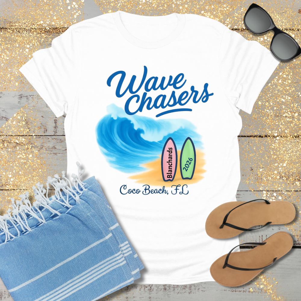 White t-shirt with 'Wave Chasers' design, sunglasses, towel, and flip-flops on a wooden surface.