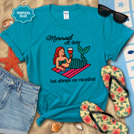 Blue t-shirt with mermaid graphic and text on a beach setting