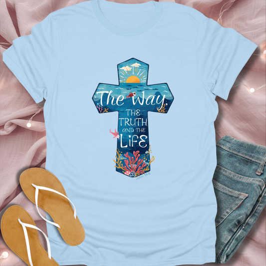 Light blue t-shirt with a colorful cross design and text on a pink fabric background.