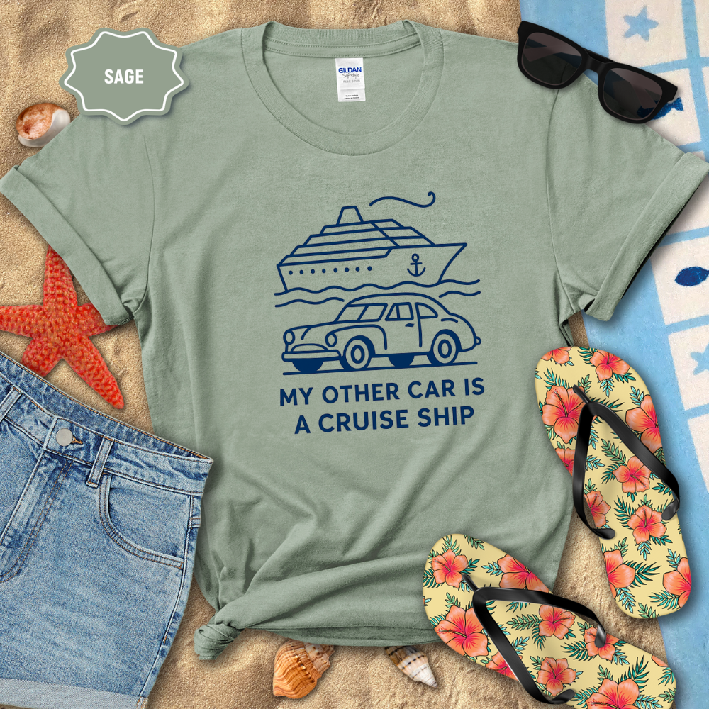 Sage green t-shirt with a graphic and text 'My other car is a cruise ship' on a beach setting with sunglasses, flip-flops, and starfish.