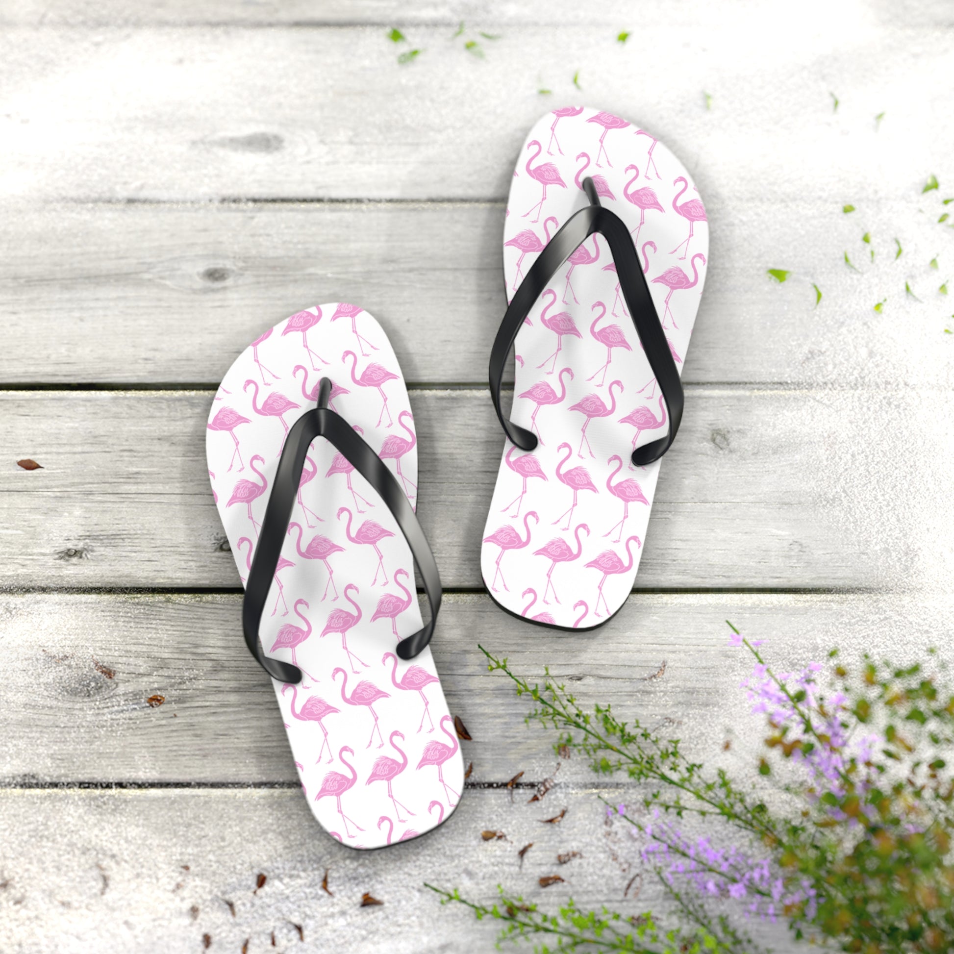 Pair of flip-flops with colorful pattern on a wooden surface with flowers.