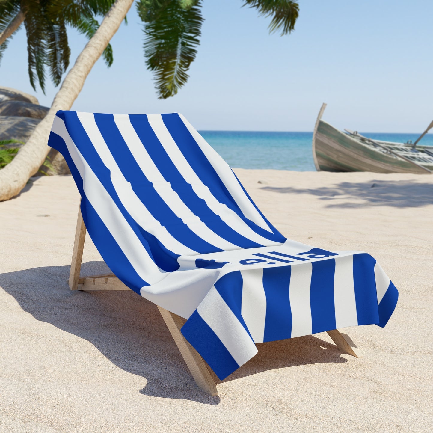 Blue and white striped towel draped over a beach chair on a sandy beach with palm trees and ocean in the background.
