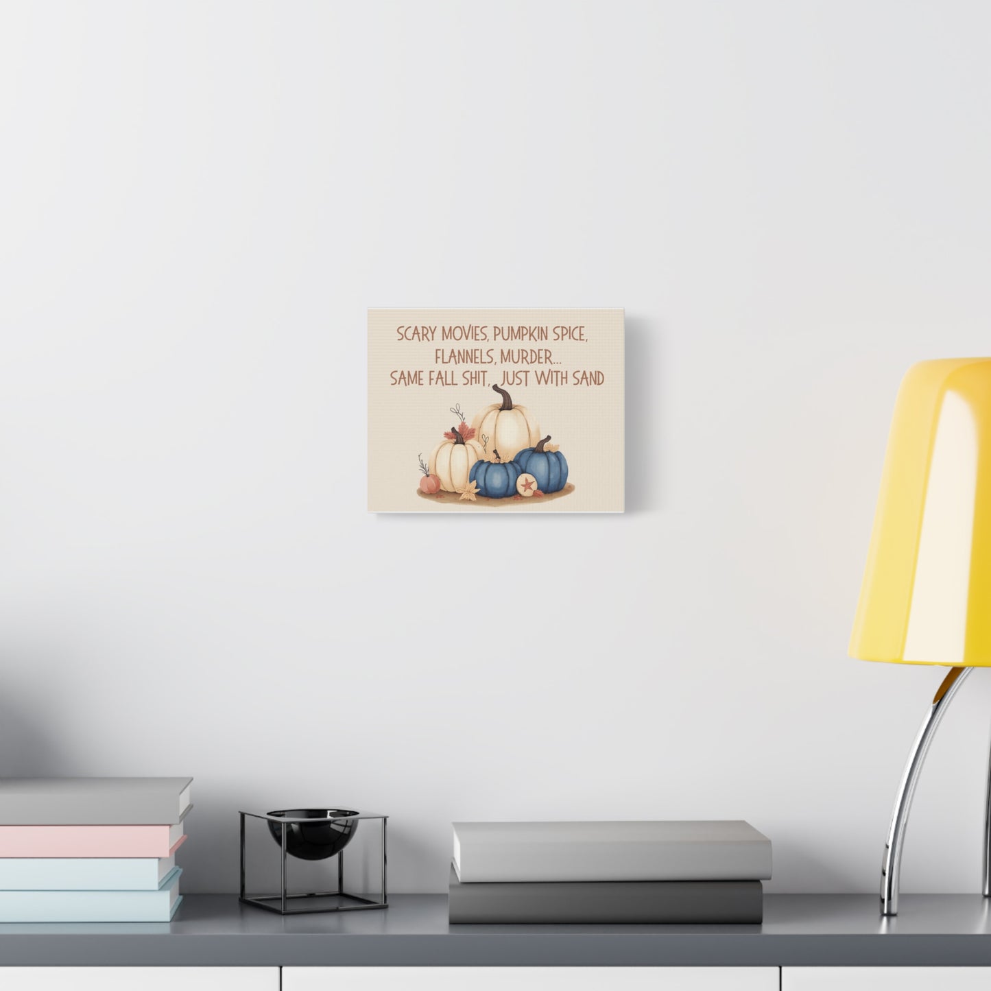 Decorative wall art with pumpkins on a shelf against a white wall.