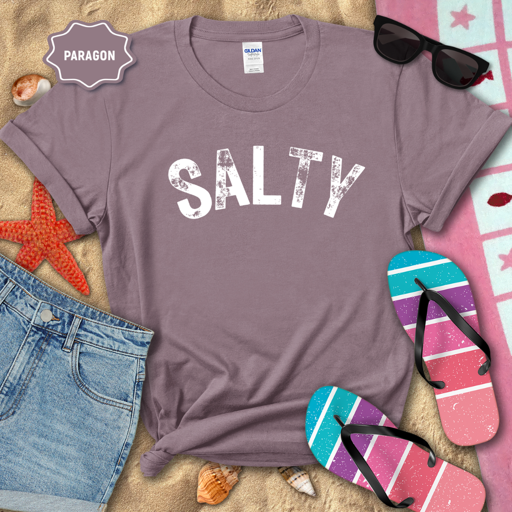 Purple t-shirt with 'SALTY' text on a beach-themed background with sunglasses, flip-flops, and denim shorts.