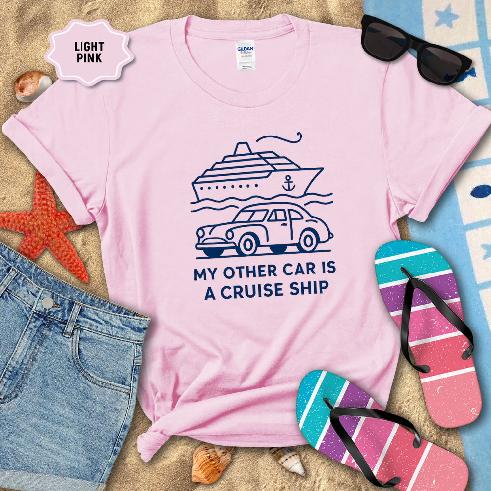 Light pink t-shirt with a cruise ship graphic and text, surrounded by beach accessories.
