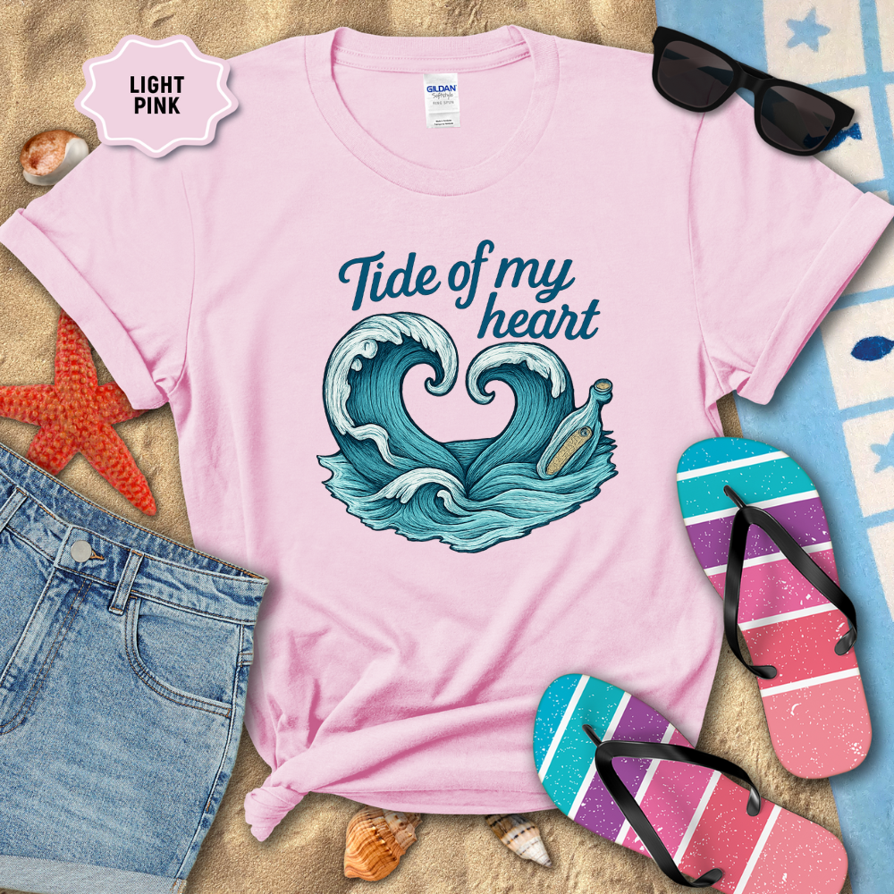 Light pink t-shirt with wave design and 'Tide of my heart' text, surrounded by beach accessories.