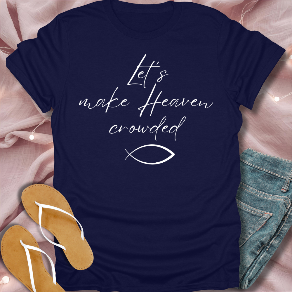Navy blue t-shirt with 'Let's make Heaven crowded' text and fish symbol on a pink fabric background.
