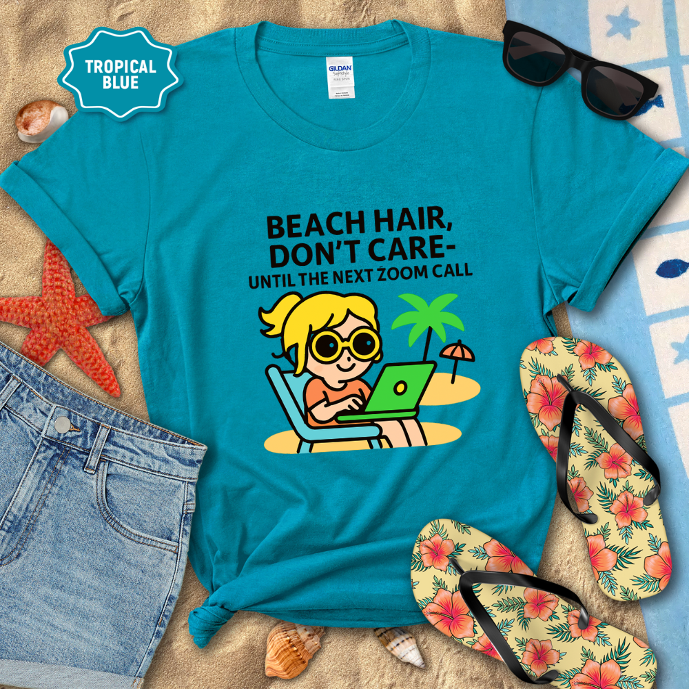 Blue t-shirt with beach-themed design and text on a sandy background with flip-flops and sunglasses.