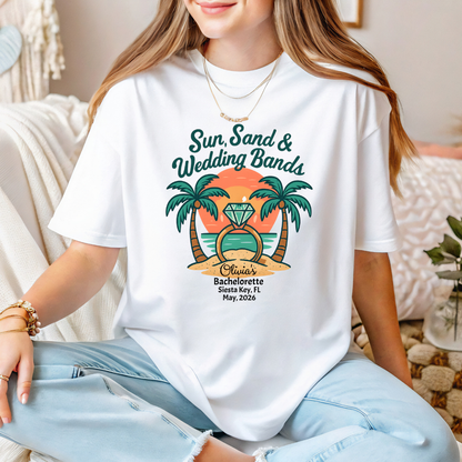 Person wearing a white t-shirt with a tropical design and text, sitting on a couch.