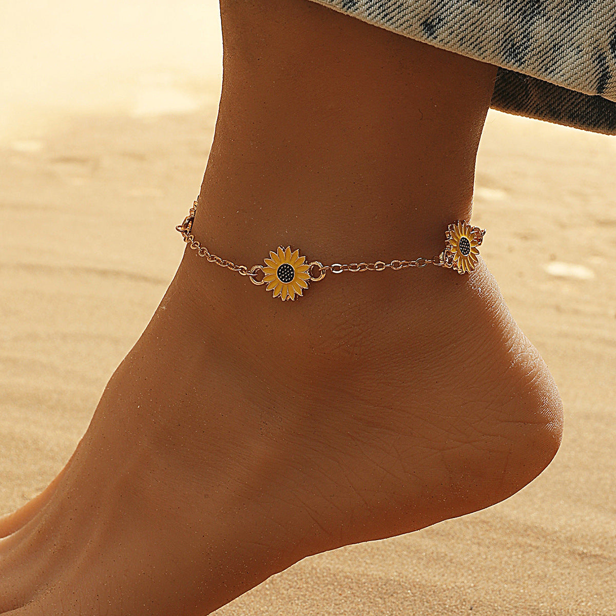 Anchored anklet with sunflower design on a sandy background