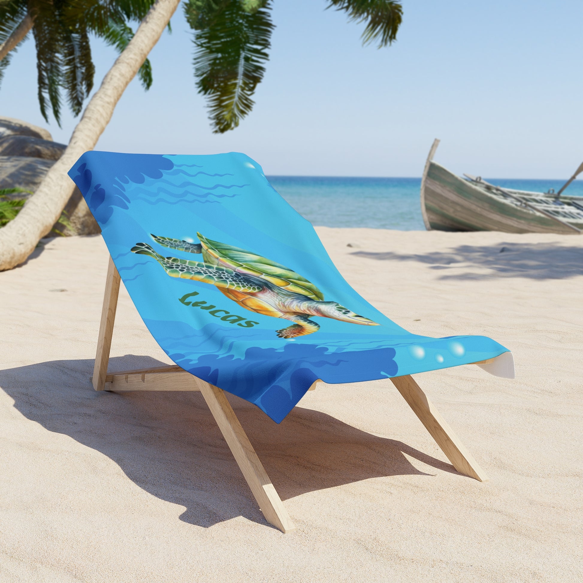 Beach towel with turtle design and 'Lucas' text on a sand chair by the ocean.
